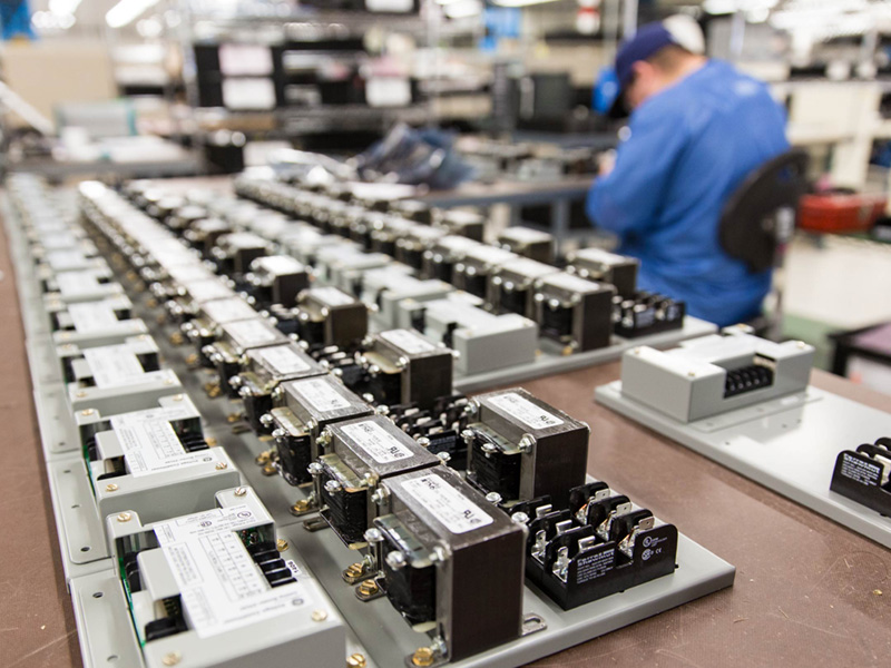 row of devices in a lab with a person working in the background